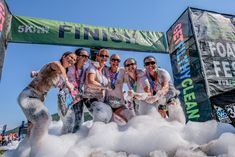 a group of people standing on top of foam in front of a race finish line