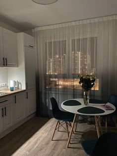 a dining table and chairs in a small room with white curtains on the windowsill