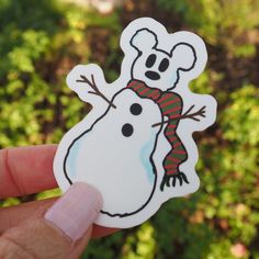 a person holding up a sticker with a snowman on it