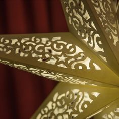 an intricately designed light fixture in front of a red curtain