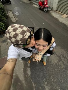 a man and woman kissing on the street with scooters parked in the background