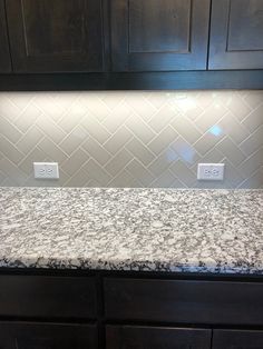 a kitchen counter top with white tile and dark wood cabinets in the backround