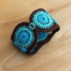 two crocheted blue and brown rings sitting on top of a wooden table next to each other