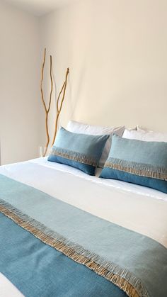 a bed with blue and white pillows on top of it