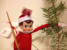 an elf holding a broom next to a pine tree with snow on its head and arms