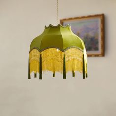 a green and yellow chandelier hanging from a ceiling in a room with a painting on the wall