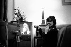 black and white photograph of a woman sitting on a couch in front of a television