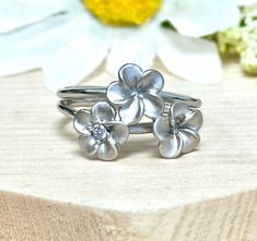 Hawaiian Plumeria Ring 925 Sterling Silver * Height: 13mm * Solid 925 Sterling Silver * Ring box included Processing and Shipping Details Ready to ship within 1-2 business days. USPS First Class mail is used for standard shipping. A tracking number is provided via email when the package is shipped. Faster shipping option is available.  Maintenance  Cleaning/Polishing - It is recommended to use a jewelry polishing cloth to clean silver jewelry.  It is also recommended to use jewelry cleaning solution every few months. Care - Proper maintenance is needed for color plated rings. Avoid contact with strong chemicals, household cleaning products, strong personal care products (lotion, perfume, sanitizer). Avoid contact with abrasive and rough surfaces. Returns and Exchanges There is a 15% restoc Adjustable White Gold Flower Ring For Anniversary, Adjustable White Gold Flower Ring Gift, Plumeria Ring, Clean Silver Jewelry, Trendy Bridesmaids, Flowers Ring, Hawaiian Plumeria, Jewelry Cleaning, Cleaning Silver Jewelry