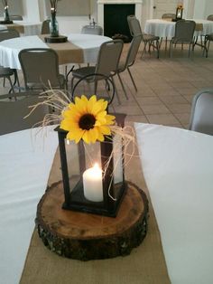 a centerpiece with a sunflower and two lit candles on top of a table