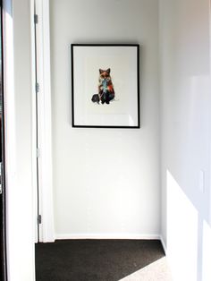 an empty room with white walls and a black framed animal on the wall above it