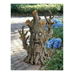 a tree stump with an evil face on it's head and eyes, sitting in the middle of a garden