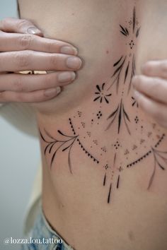 a woman's back with tattoos on her chest and hands holding the top part of her stomach