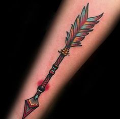 an arrow tattoo on the arm with feathers and a feather blade in it's center