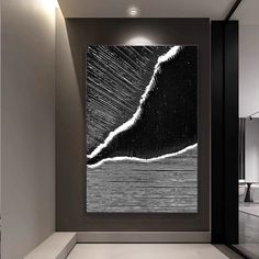 an abstract black and white painting hangs on the wall