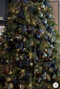 a decorated christmas tree in a living room with blue and green ornaments on the top