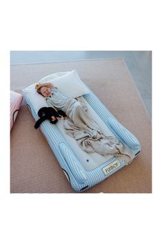 a baby laying on top of an inflatable mattress with a cat sleeping on it