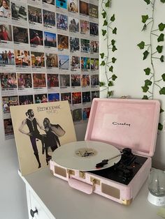 a record player sitting on top of a white table next to a wall covered with pictures