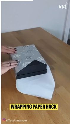 someone is wrapping paper on top of a table with their hands and fingers touching it