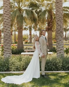 a bride and groom standing in front of palm trees