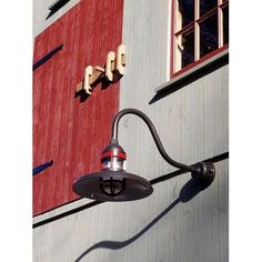 a lamp on the side of a building next to a red and gray wall with windows