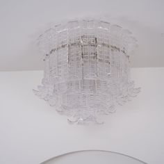 a glass light fixture hanging from the ceiling in a room with white walls and flooring