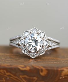 a white diamond ring on top of a wooden box with diamonds around the band and center stone