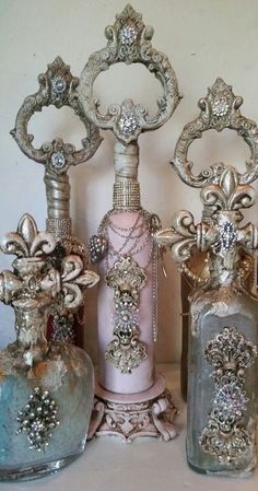 three glass vases sitting next to each other on top of a table in front of a white wall