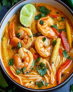 a bowl filled with shrimp, corn and cilantro soup on top of a table