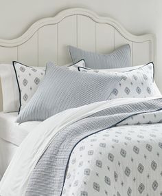 a bed with white headboard and blue comforter in front of a large window