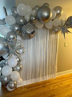 silver and white balloons are hanging on the wall