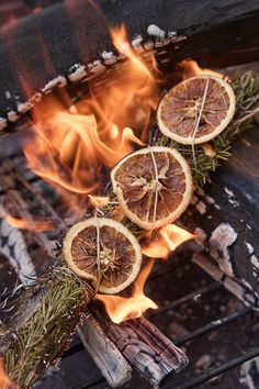 some oranges are sitting on sticks in the fire