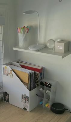 a white desk with various office supplies on it and a shelf above the desk filled with books