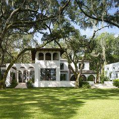 a large white house surrounded by trees and grass