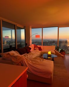 a living room filled with furniture and large windows overlooking the city at sunset or dawn