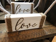 two wooden signs that say love and one says love on them with rope hanging from the sides