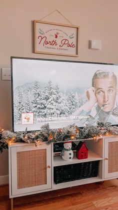 a christmas scene is displayed in front of a large poster on the wall above a entertainment center