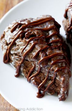 a white plate topped with chocolate scones covered in icing