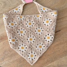 a crocheted bag with yellow and white flowers hanging from it's side