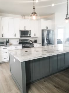 a large kitchen with white cabinets and marble counter tops, along with stainless steel appliances