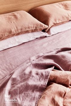 an unmade bed with pink sheets and pillows