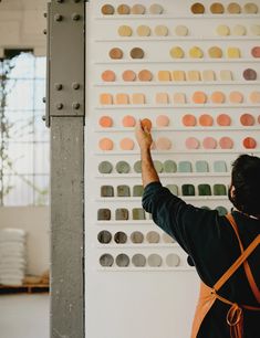 a person standing in front of a wall with different colored circles on it and pointing at something