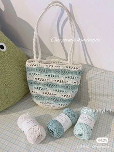 two balls of yarn and a crochet bag on a table