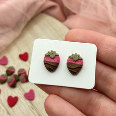 a pair of strawberry shaped earrings sitting on top of a white card