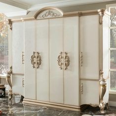 a white and gold armoire sitting next to a large window in a living room