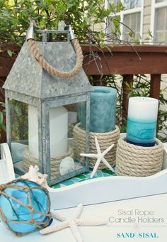 a table topped with candles and other items on top of a white table covered in sand