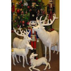 three white deer statues in front of a christmas tree and nutcrackers on the floor