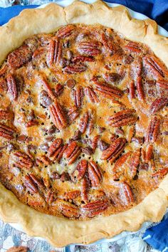 a pie with pecans on it sitting on top of a blue and white cloth