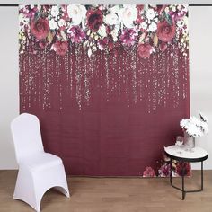 a white chair sitting in front of a red wall with flowers on it's side