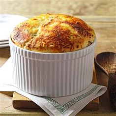 a casserole in a white dish on top of a wooden table next to spoons