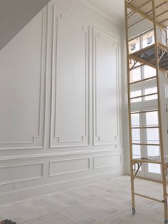 an empty room with white walls and a ladder